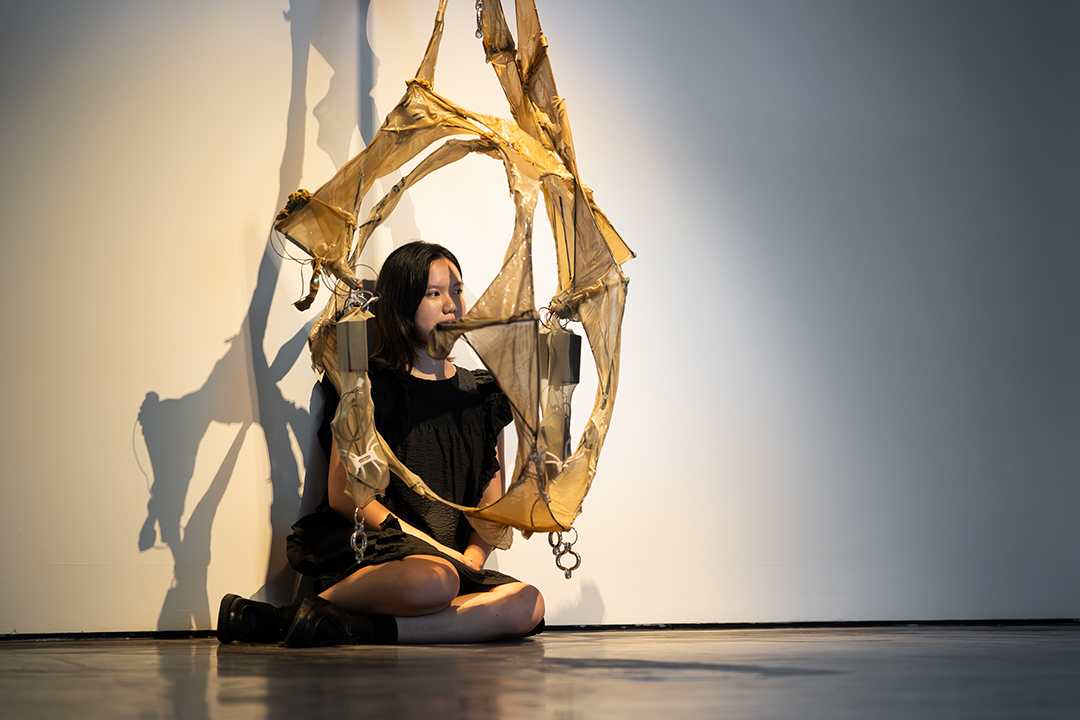 An artist wearing black with her installation artwork